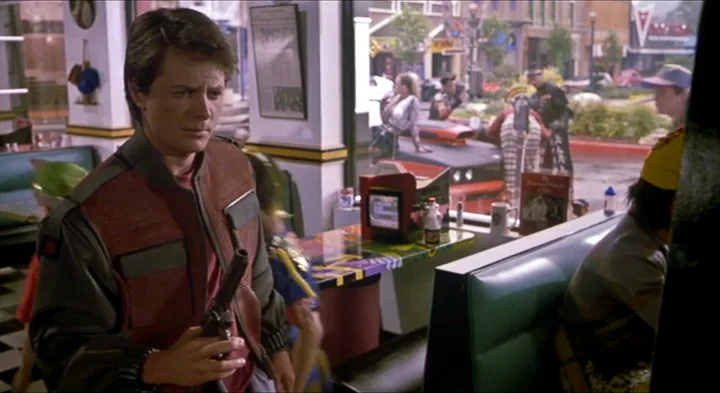 Fütüristik bir kafede içecek şişesi tutan Marty McFly